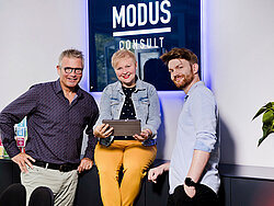 Jobs bei MODUS Consult. Zwei Kollegen und eine Kollegin lächeln freundlich in die Kamera.