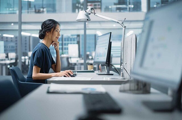 Junge Frau sitzt vor einem Computer und schaut auf dem Monitor. Headerbild für unsere Referenzen zu ELO.
