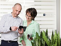 Herr und Dame schauen auf ein mobiles Gerät
