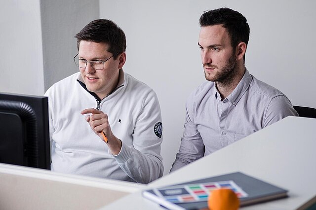 Zwei Herren schauen auf einen Monitor